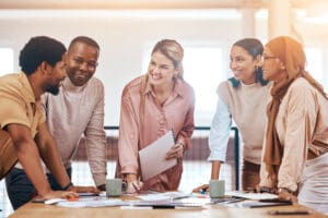 Diverse group of professionals collaborating in a modern office, smiling and engaged in a discussion, representing a positive workplace culture fostered by HR.
